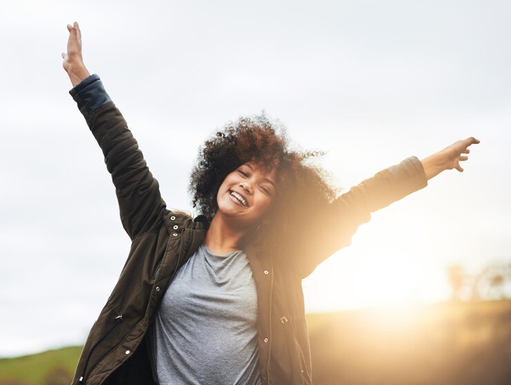 Photo life is for celebrating portrait of a joyful young woman raising her hands in nature