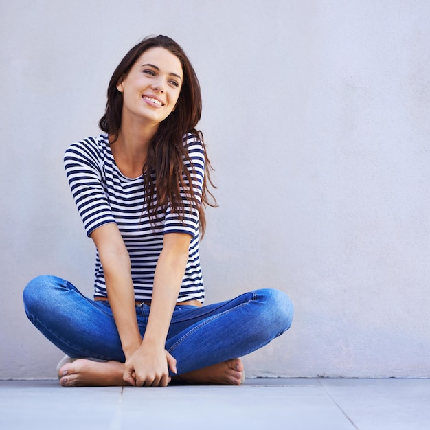 Life is just grand A beautiful young woman looking thoughtful while sitting crosslegged on the floor