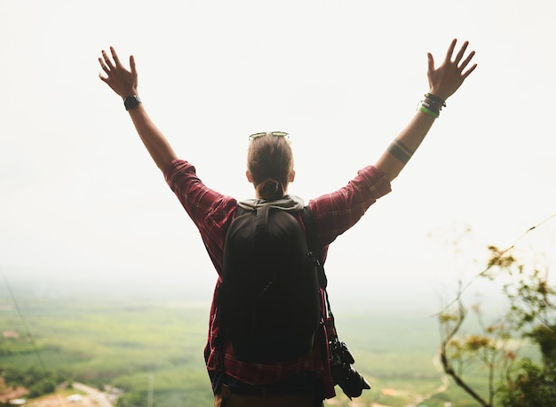 Life is meant to be lived Rearview shot of a young man standing atop a mountain with his arms outstretched