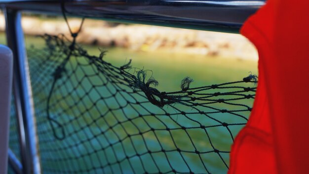 Life jacket and net on boat. Safety net on boat. Ropes on boat. Safety ropes and blue sea. Waves on the sea and safety mesh.