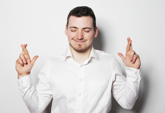Photo life style business and people concept business man in shirt keeping fingers crossed while standing against white background