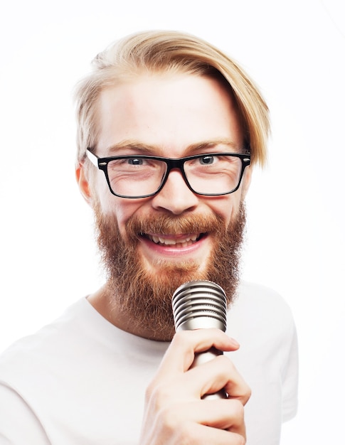 Concetto di stile di vita: un giovane con la barba che indossa una camicia bianca con in mano un microfono e canta.isolato su bianco.