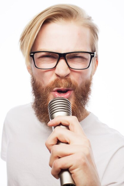 Concetto di stile di vita: un giovane con la barba che indossa una camicia bianca con in mano un microfono e canta.isolato su bianco.