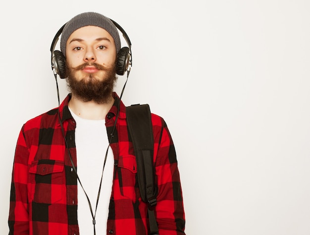 Stile di vita, educazione e concetto di persone: giovane uomo barbuto che ascolta musica mentre si trova su uno sfondo grigio. stile hipster.