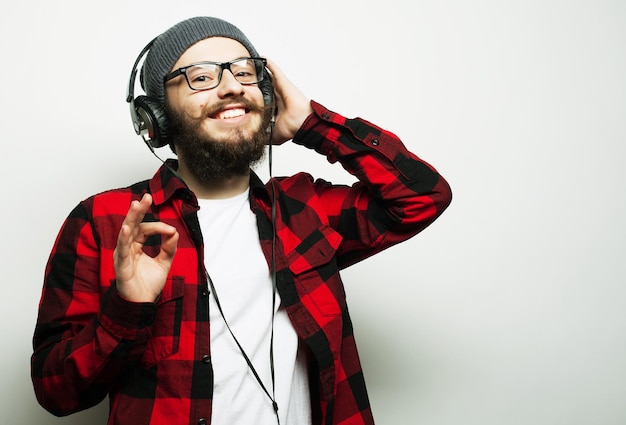 Образ жизни образование и концепция людей молодой бородатый мужчина слушает музыку, стоя на сером фоне хипстерский стиль