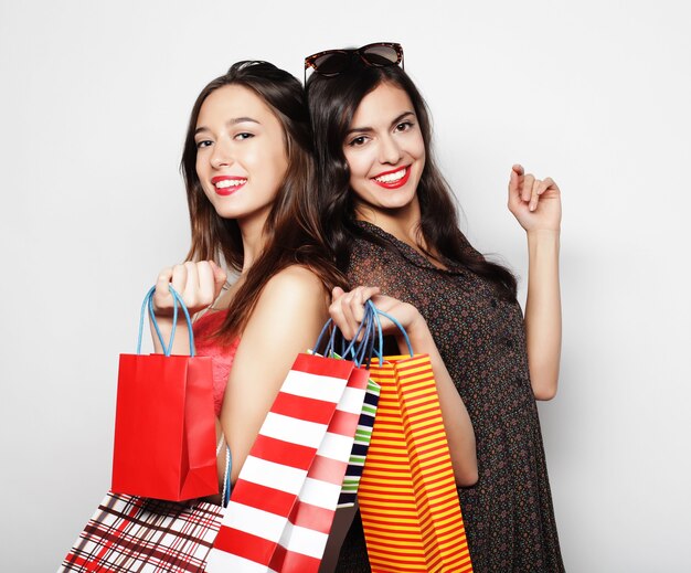Life style, happiness, emotional and people concept: Beautiful teen girls carrying shopping bags, over white background
