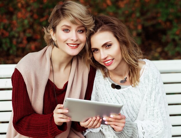 Life style, happiness, emotional and people concept: beautiful women girls autumn using tablet outdoor