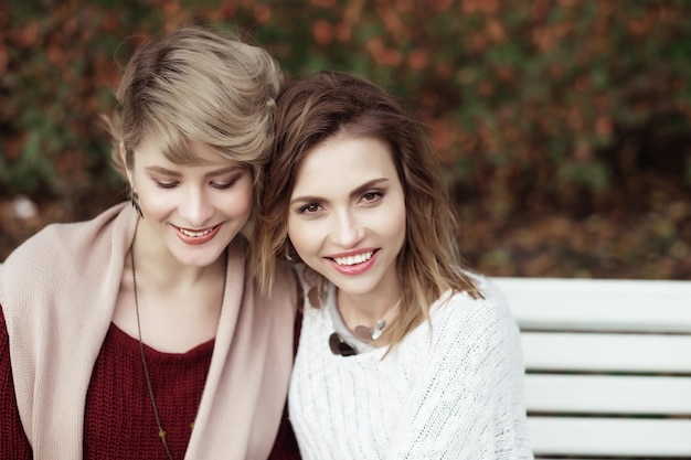 life style happiness emotional and people concept beautiful young women sitting on a bench in the autumn park