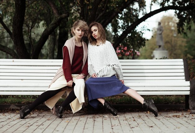 life style happiness emotional and people concept beautiful young women sitting on a bench in the autumn park