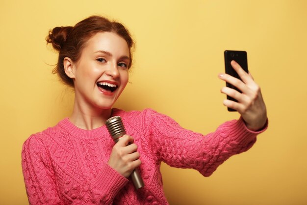 Stile di vita felicità emotiva e concetto di persone bellezza ragazza con un microfono che canta e si fa selfie