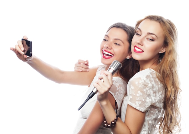 Stile di vita, felicità, concetto emotivo e di persone: ragazze di bellezza con un microfono che cantano e fanno selfie