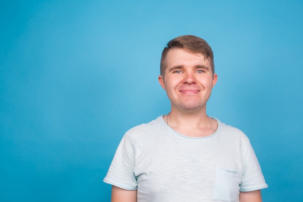 Life style and people concept - Happy handsome young man wearing blue t-shirt over blue background