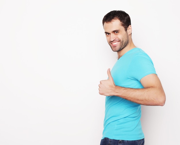 Foto stile di vita e concetto della gente: giovane felice in camicia blu che mostra i pollici su. su sfondo bianco.