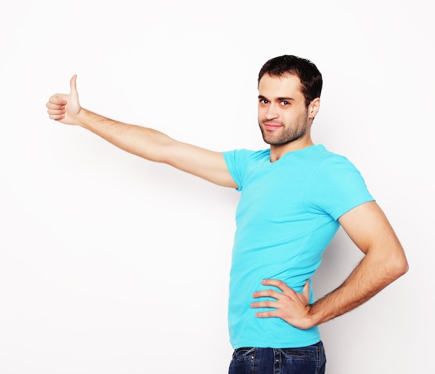 Photo life style  and people concept: happy young man in blue shirt  showing thumbs up. over white background.