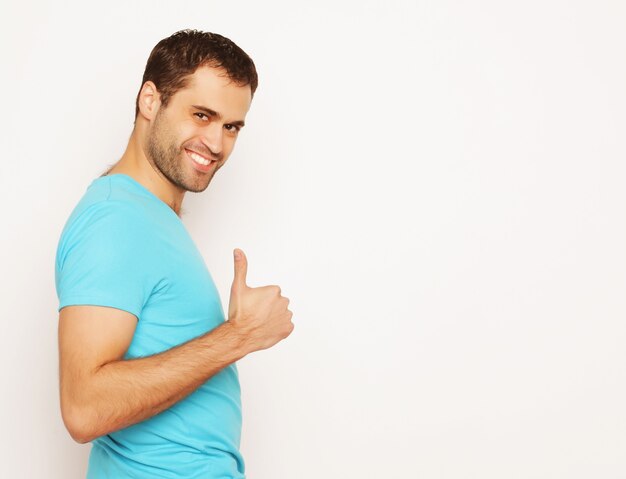 Life style and people concept: happy young man in blue shirt showing thumbs up