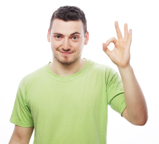 life style and people concept young casual man showing the victory gesture while smiling for the camera with a hand in his pocketIsolated on white background