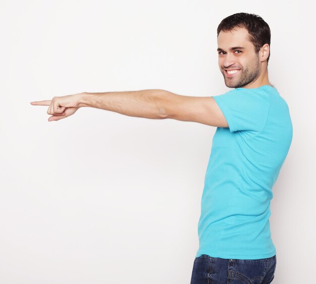 Foto stile di vita e concetto di persone giovane uomo felice sorridente mostra qualcosa su sfondo bianco