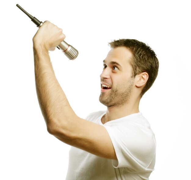 Life style, people and leasure concept: a young man wearing a white shirt holding a microphone and singing. Isolated on white.