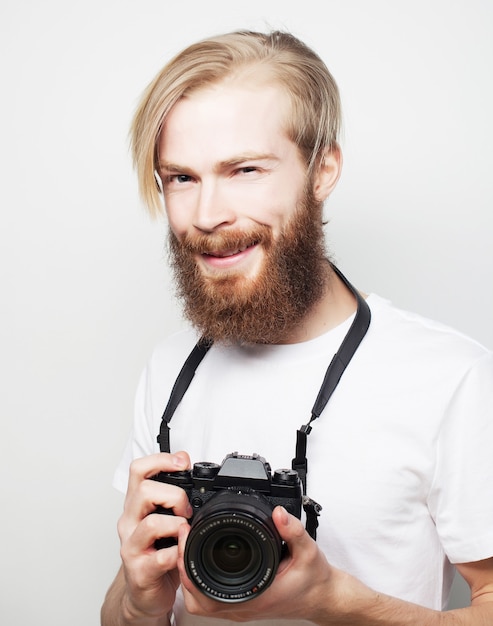 Фото Концепция образа жизни, технологий и путешествий: бородатый мужчина в белой футболке с цифровой камерой, изолированной на белом фоне