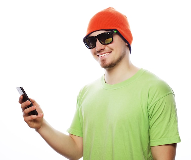 life style tehnology and people concept cheerful man in green shirt and bright hat using smartphone isolated on white