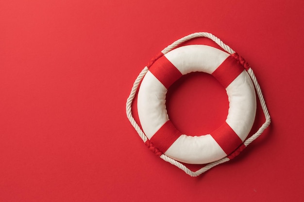 Photo lifebuoy on a red background with copy space on the left side of the frame top view