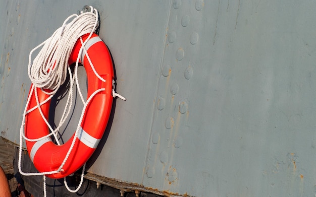 The lifebuoy with cord is hanged on metal wall on the ship