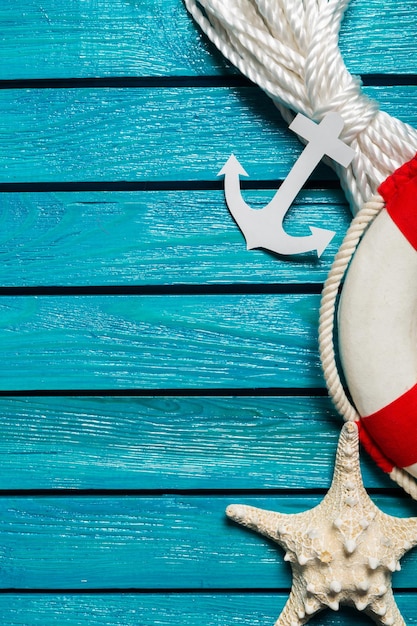 Lifebuoy with seashell and anchor on blue wooden background. Travel concept