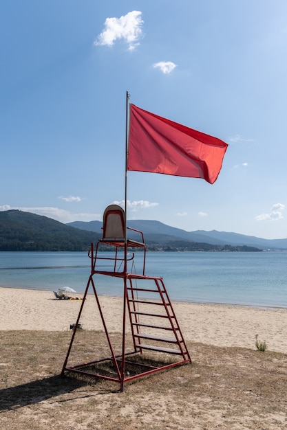 Lifeguard chair with red flag waving. No swimming concept