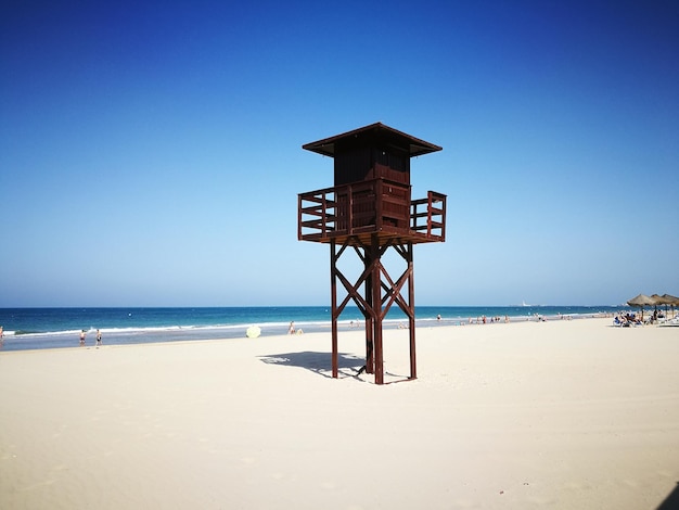 Foto cotta di soccorritore sulla spiaggia contro un cielo blu limpido