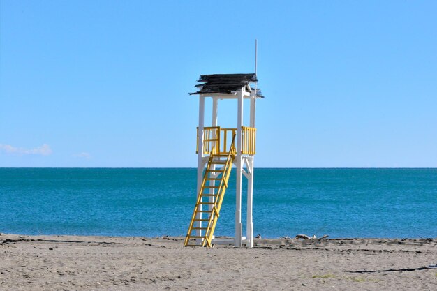 Lifeguard hut on beach against clear blue sky