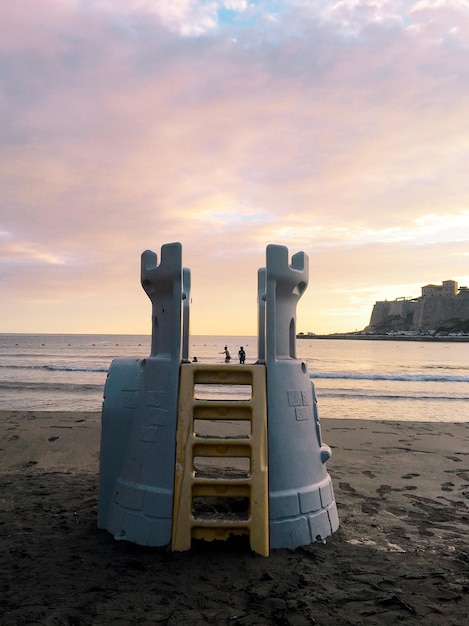 Photo lifeguard hut on beach against sky during sunset