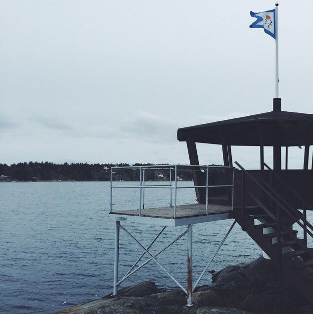 Lifeguard hut by river against sky