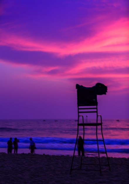 写真 夕暮れの空に照らされたビーチのライフガードハット