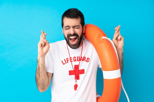 Lifeguard man over blue with fingers crossing