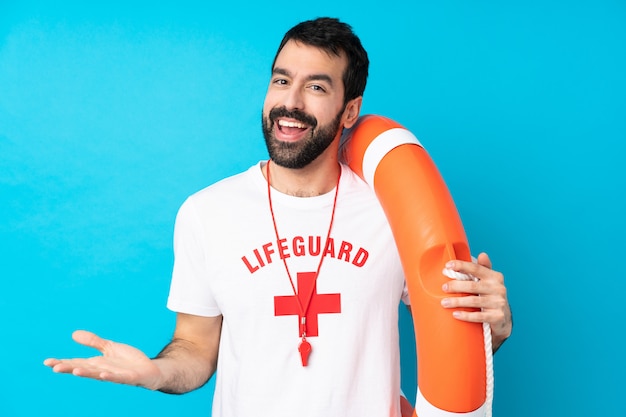 Lifeguard man over isolated blue wall smiling