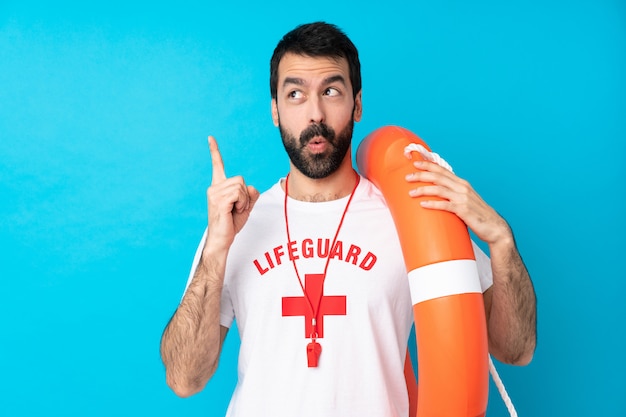 Lifeguard man over isolated blue wall thinking an idea pointing the finger up