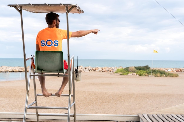 Спасатель сидит на стуле на пляже