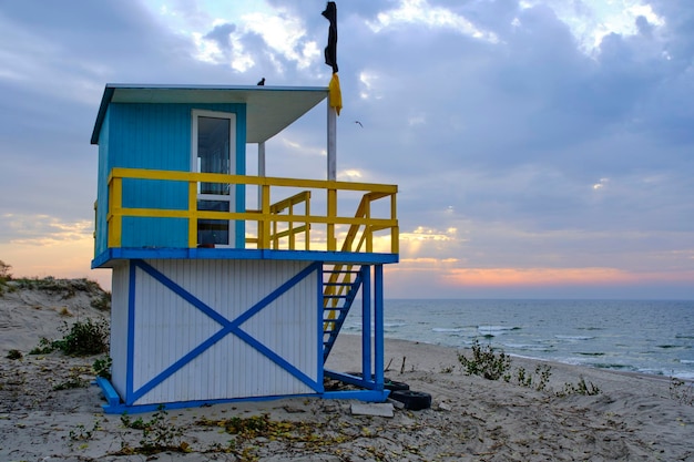 Lifeguard tower sandy sea beach with a raised black flag meaning swimming is prohibited