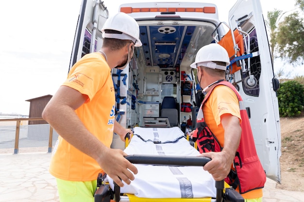 Спасатель в униформе на носилках из машины скорой помощи