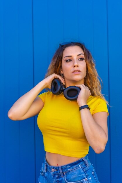 Lifestyle, blonde Caucasian girl with yellow t-shirt. Sexy girl and dj with headphones smiling