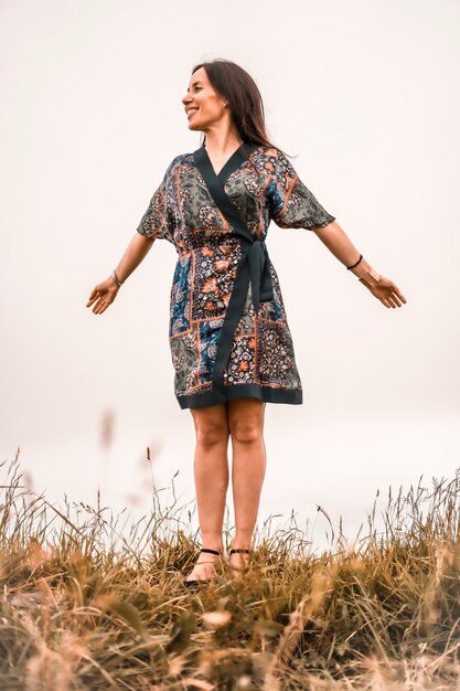 Lifestyle, brunette girl enjoying nature with colorful dress on top of a mountain