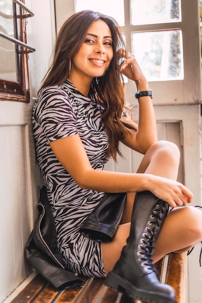 Lifestyle a Caucasian brunette close to a window with leather boots