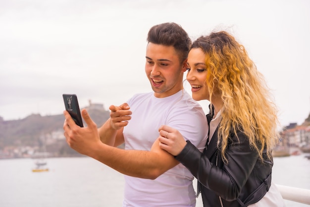 Lifestyle of a Caucasian couple sightseeing on vacation, by the sea taking a photo and smiling