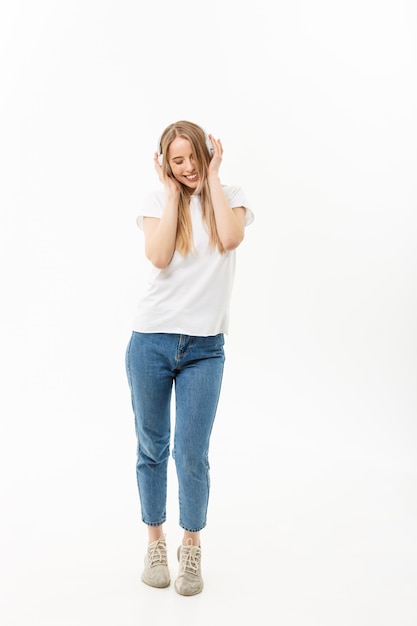 Lifestyle Concept: Portrait of a cheerful happy girl student listening to music with headphones while dancing