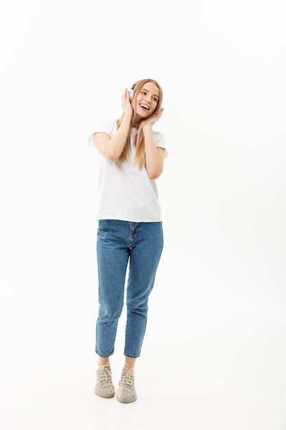 Lifestyle Concept: Portrait of a cheerful happy girl student listening to music with headphones while dancing