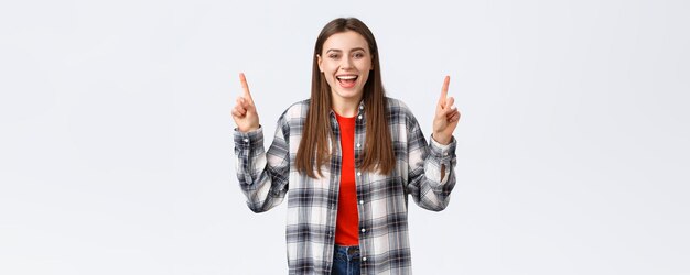 Lifestyle different emotions leisure activities concept Happy beautiful girl in checked shirt pointing fingers up and laughing carefree showing good summer vacation ideas promo or banner