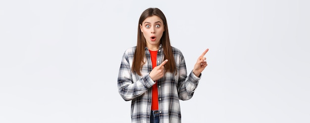 Lifestyle different emotions leisure activities concept Wow amazing look here Astonished young speechless girl showing cool new promo pointing fingers upper right corner and stare camera