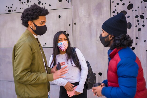 Lifestyle, drie vrienden praten op straat en hebben plezier met gezichtsmaskers.