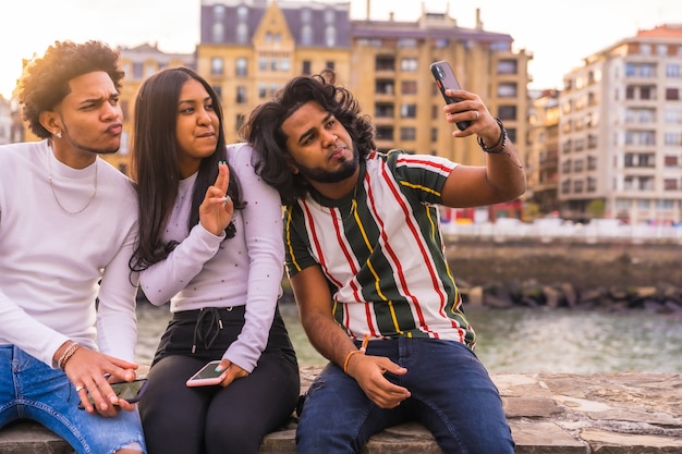 Lifestyle, drie zwarte vrienden die plezier hebben en een selfie maken. Afro haar jongen, brunette jongen met lang haar en donkerbruin meisje