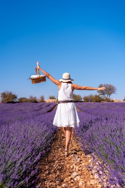 Lifestyle een vrouw in een zomers lavendelveld in een witte jurk genietend van de natuur